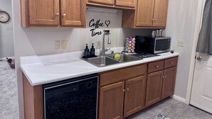 A compact kitchen with wooden cabinets, a dishwasher, a sink, and a microwave. - Terry Townhouse Two (Cave City)