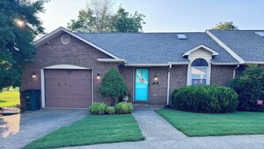 A two-story house with a brown garage door, a blue front door, and a small porch area. - Terry Townhouse Two (Cave City)