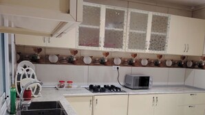 A kitchen with a granite countertop, stainless steel sink, white cabinets, a microwave, and a gas stove.