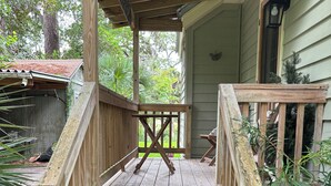 A wooden porch with a railing, leading to a house with a green exterior. - Peace Like A River is a charming one room efficiency,  private entrance. (Bluffton)