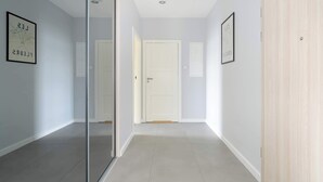 A hallway with a glass partition, light-colored walls, and a wooden door.