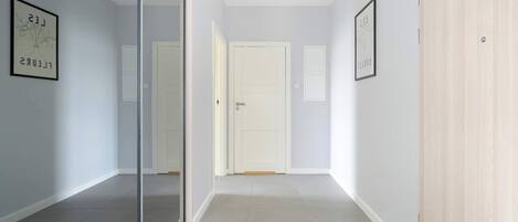 A hallway with a glass partition, light-colored walls, and a wooden door.