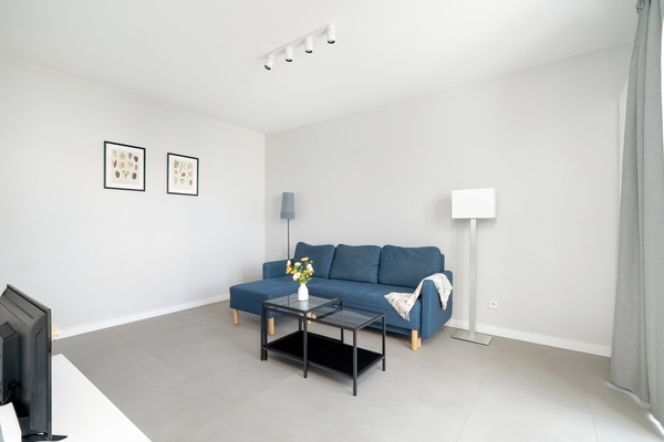A modern living room with a blue sofa, coffee table, and minimalistic décor in neutral tones.