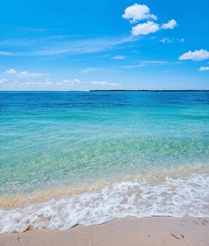A beach with clear turquoise water, gentle waves, and a distant landmass under a clear sky. - Spa 🌴Tropical Waterfront 🏝️Heated Pool🏖️Beach (Port Charlotte)