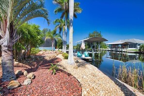 A serene lakeside setting with a dock, lounge chairs, and a covered seating area.