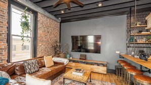Een moderne woonkamer met een leren bank, een houten salontafel en een bar voorzien van krukken.