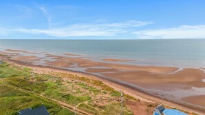 Eine Küstenlandschaft mit Sandstrand und blauem Himmel.