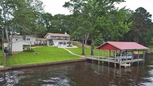 Una casa con un muelle que se adentra en un lago, rodeada de árboles.