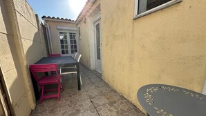 Un pequeño patio con una mesa, sillas, una puerta y una ventana.