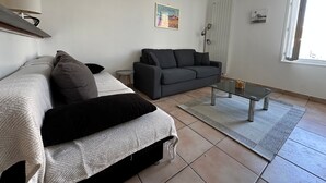 Una sala de estar con un sofá, un sillón más pequeño, una mesa de centro y una lámpara.