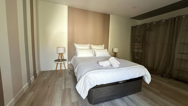 Un dormitorio moderno con una cama grande, dos lámparas de noche y un cabecero oscuro.