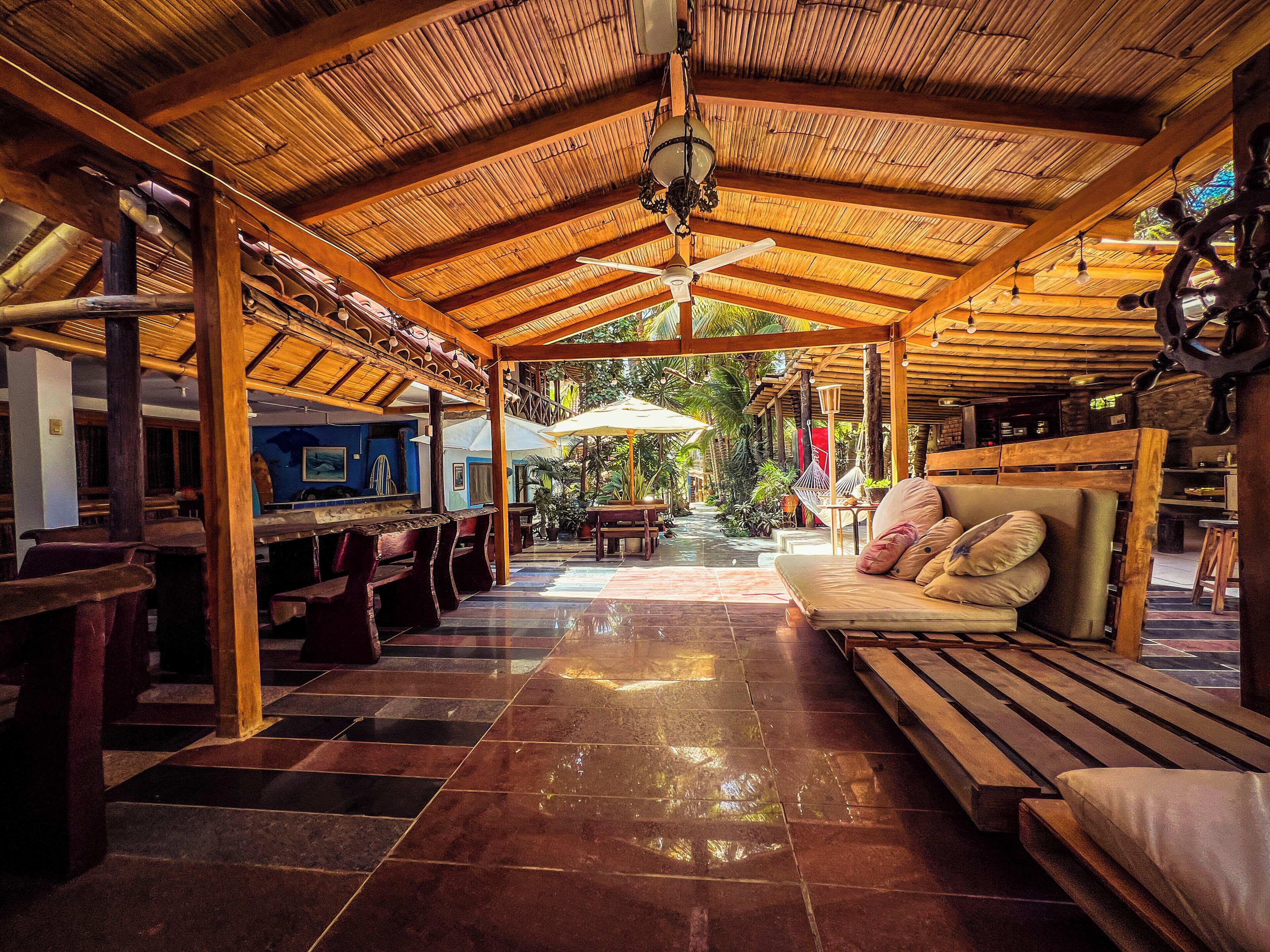 A covered outdoor seating area with wooden benches and tables, a ceiling fan, and a view of the outdoors.