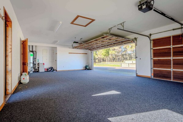 A spacious garage with a concrete floor, a wooden door, and a large garage door.