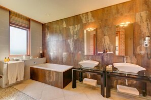 Un baño moderno con una bañera grande, dos lavamanos y un tocador de vidrio.
