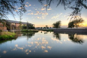 Une vue sur la rivière, avec un bâtiment, des arbres et un ciel dégagé.