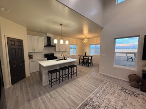 Una cocina moderna con una isla central, taburetes de bar y un comedor con vistas.