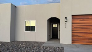 Una casa moderna con facciata grigia, una porta nera e un portone in legno.