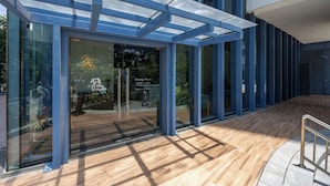 A modern building entrance with glass doors, a wooden floor, and a metal railing. - Virgo Nest Rentals - 38th Park Ave, IT Park Cebu - City View (Cebu City)