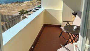 A balcony with a view of the sea, a table, and a chair. - Apartment in front of the beach of Coira in the center of Portosin (Goyanes)