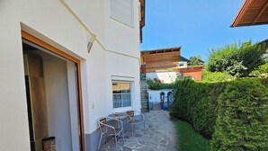 Un patio empedrado con una mesa, sillas, una puerta y una ventana.
