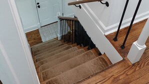 Un escalier avec des marches en bois, des murs blancs et une porte bleu clair.
