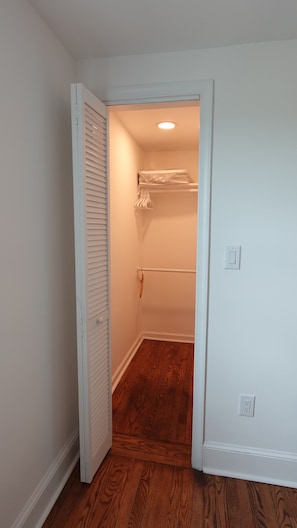 A narrow hallway leading to a closet with a wooden floor and white walls. - Cozy 3BR Retreat w/ Patio, Fire Pit & Yard (Winchester)