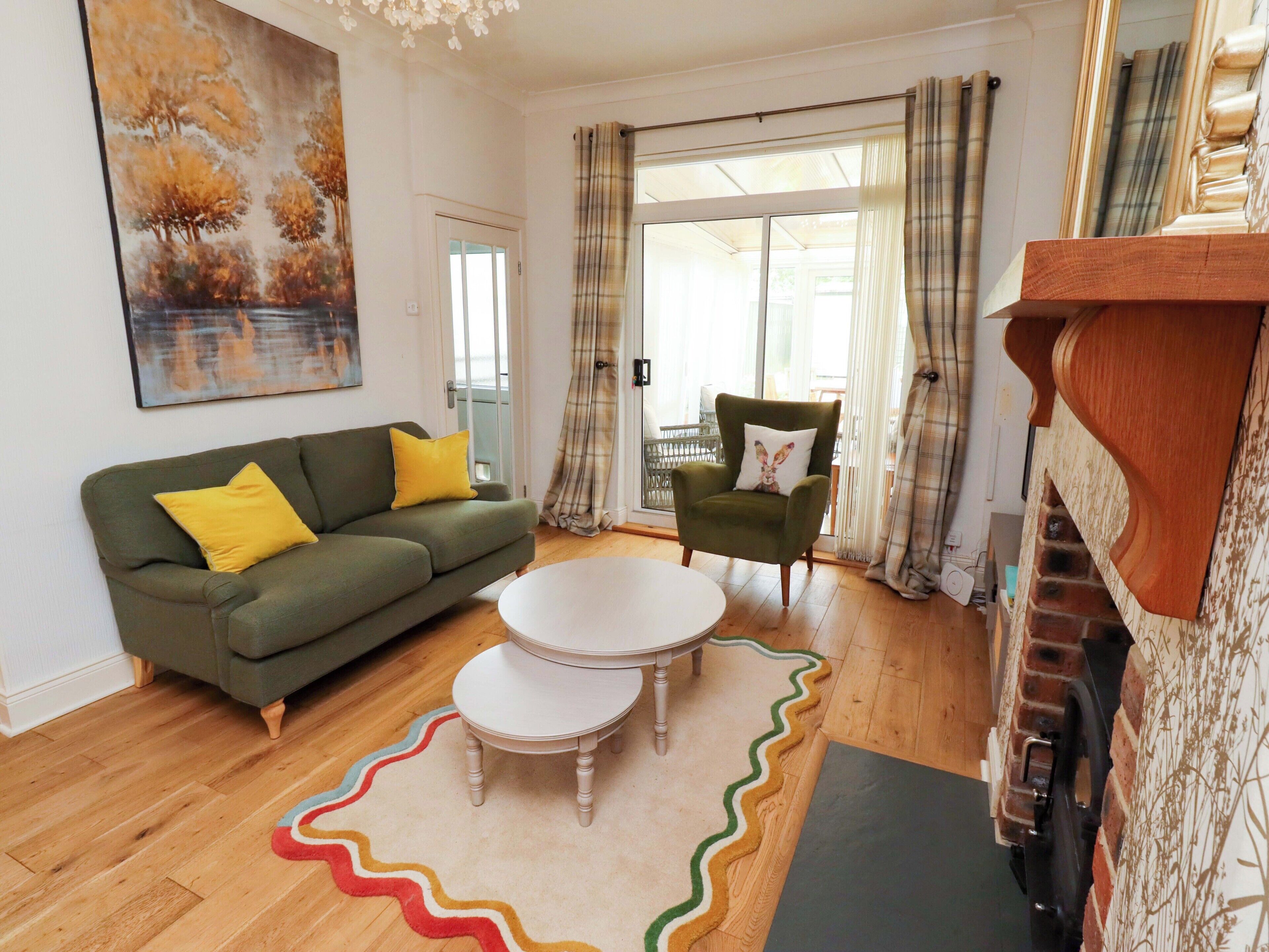 Een woonkamer met een bank, fauteuil, salontafel en een open haard.