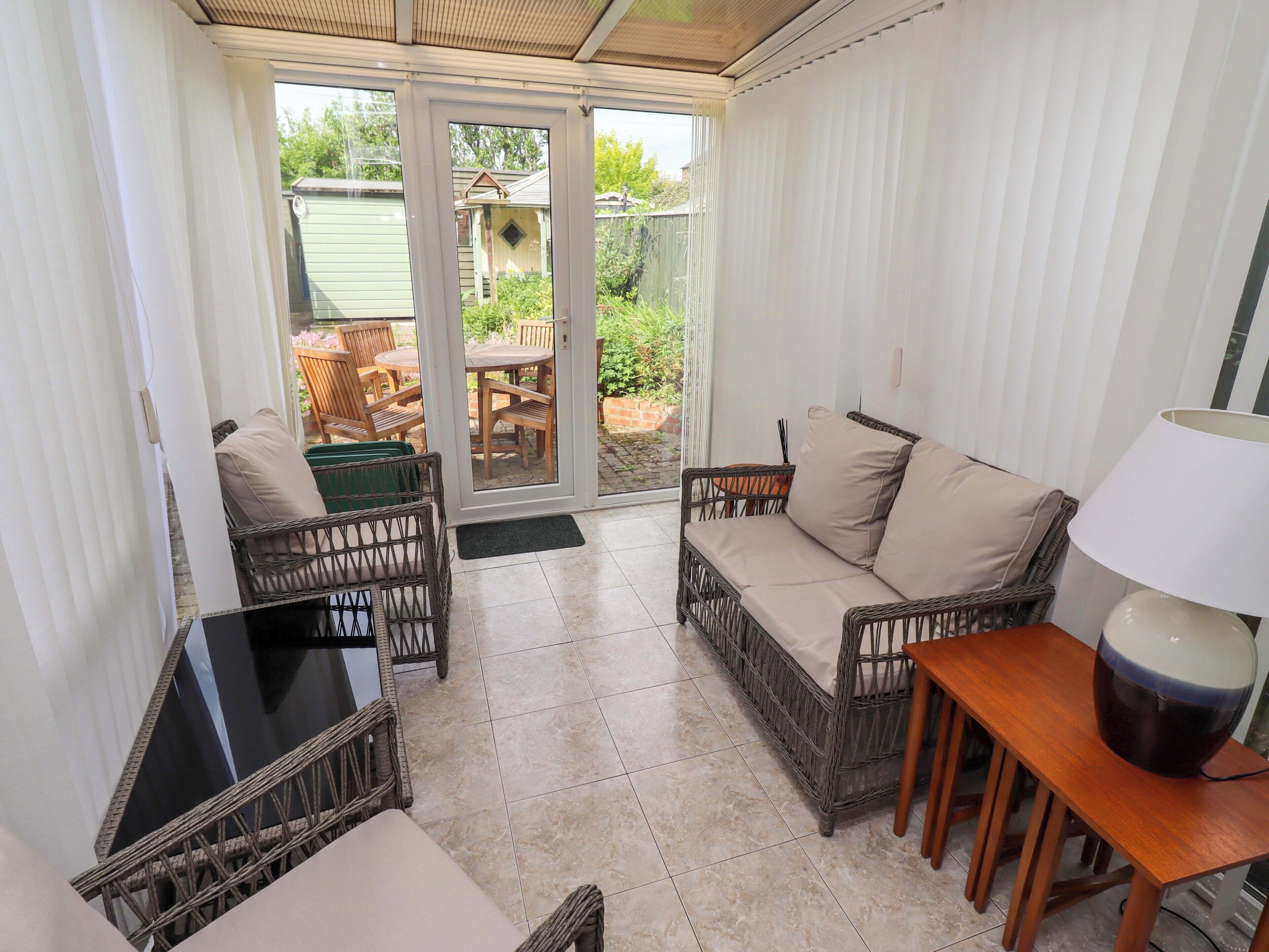 A sunroom with wicker furniture, a sofa, a table, and a lamp.