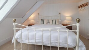 A white metal four-poster bed in a room with sloped ceilings and wooden paneling. - 84 Fore Street (Port Isaac)