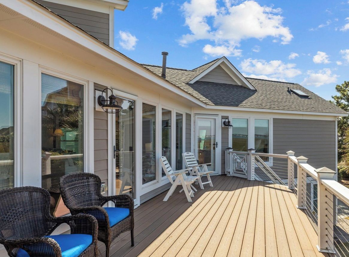 A covered deck with outdoor seating and large windows.