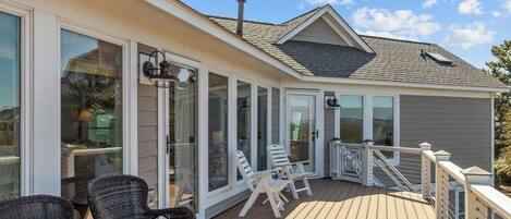 A covered deck with outdoor seating and large windows.
