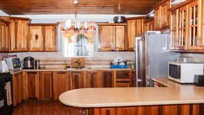 Una cocina con gabinetes de madera, un refrigerador de acero inoxidable, un microondas y un lavamanos.