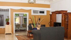 Un salón con sofá, mueble aparador, televisor y un jarrón decorativo con ramas.