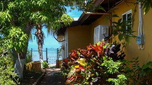 Un sendero que lleva a un edificio amarillo con vista al mar.
