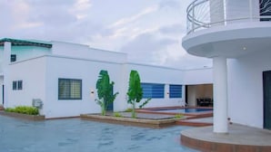 Ein modernes Gebäude mit kreisförmiger Struktur, einem Pool und einem kleinen Gartenbereich.