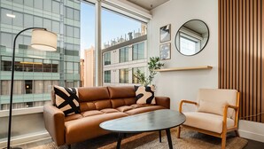 Un salon moderne avec un canapé, un fauteuil, une table ronde, un lampadaire et un miroir au mur.