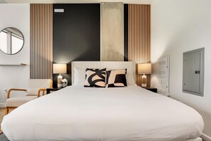 Ein Hotelzimmer mit einem großen Bett, zwei Nachttischlampen, einem runden Spiegel, einer Wandpaneelausführung aus Holz und einem Kleiderschrank.