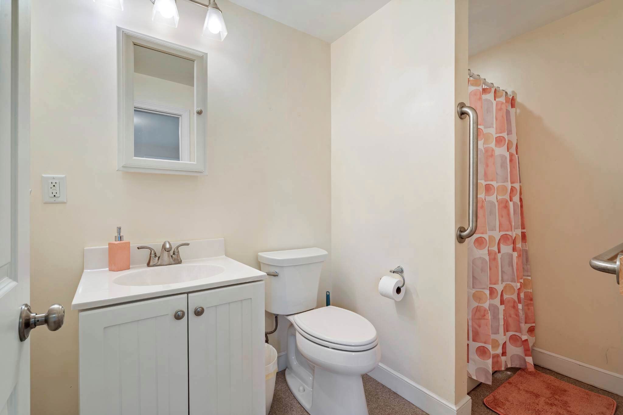 A bathroom with a white sink, toilet, and shower curtain.
