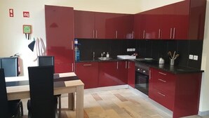 Eine moderne Küche mit roten Schränken, einer schwarzen Arbeitsplatte und einem Holzespeise Tisch.