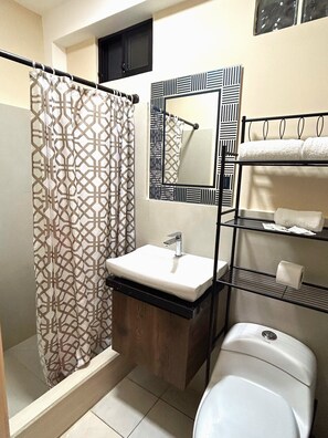 A bathroom with a shower curtain, a sink, a mirror, and a toilet. - OCEAN DRIVE LODGE MONTAÑITA (Montañita)