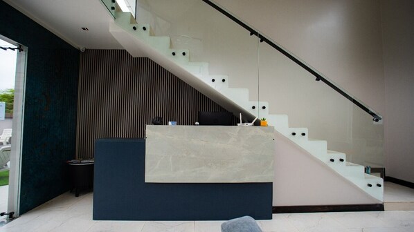 Un interior moderno con una escalera, un mostrador de recepción y una pared de color oscuro.