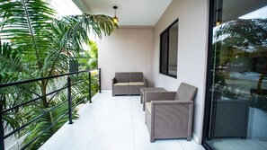 A balcony with wicker furniture, a glass railing, and lush greenery. - OCEAN DRIVE LODGE MONTAÑITA (Montañita)
