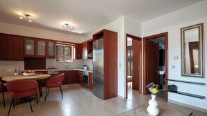 A modern kitchen with wooden cabinets, a stainless steel refrigerator, and a dining area with red chairs. - Modern flat in Chania, Crete - 5 min from the beach, 10 min from the old town! (Chania)