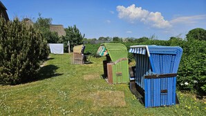 Un espacio cubierto de césped con varias estructuras, incluyendo una tienda de color azul y otra verde, además de una silla de madera.