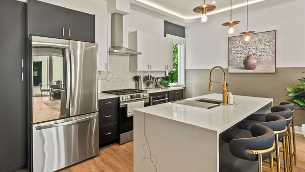 A modern kitchen with a central island, stainless steel appliances, and a bar stool area. - Upscale 3BR | Sleeps 11 | Rooftop + Parking (Dallas)