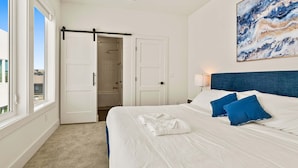 A hotel room with a bed, a bathroom, and a view of the outside. - Upscale 3BR | Sleeps 11 | Rooftop + Parking (Dallas)