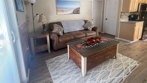 Ein Wohnzimmer mit einer braunen Ledersofa, einem Holztisch und einem Bild an der Wand.