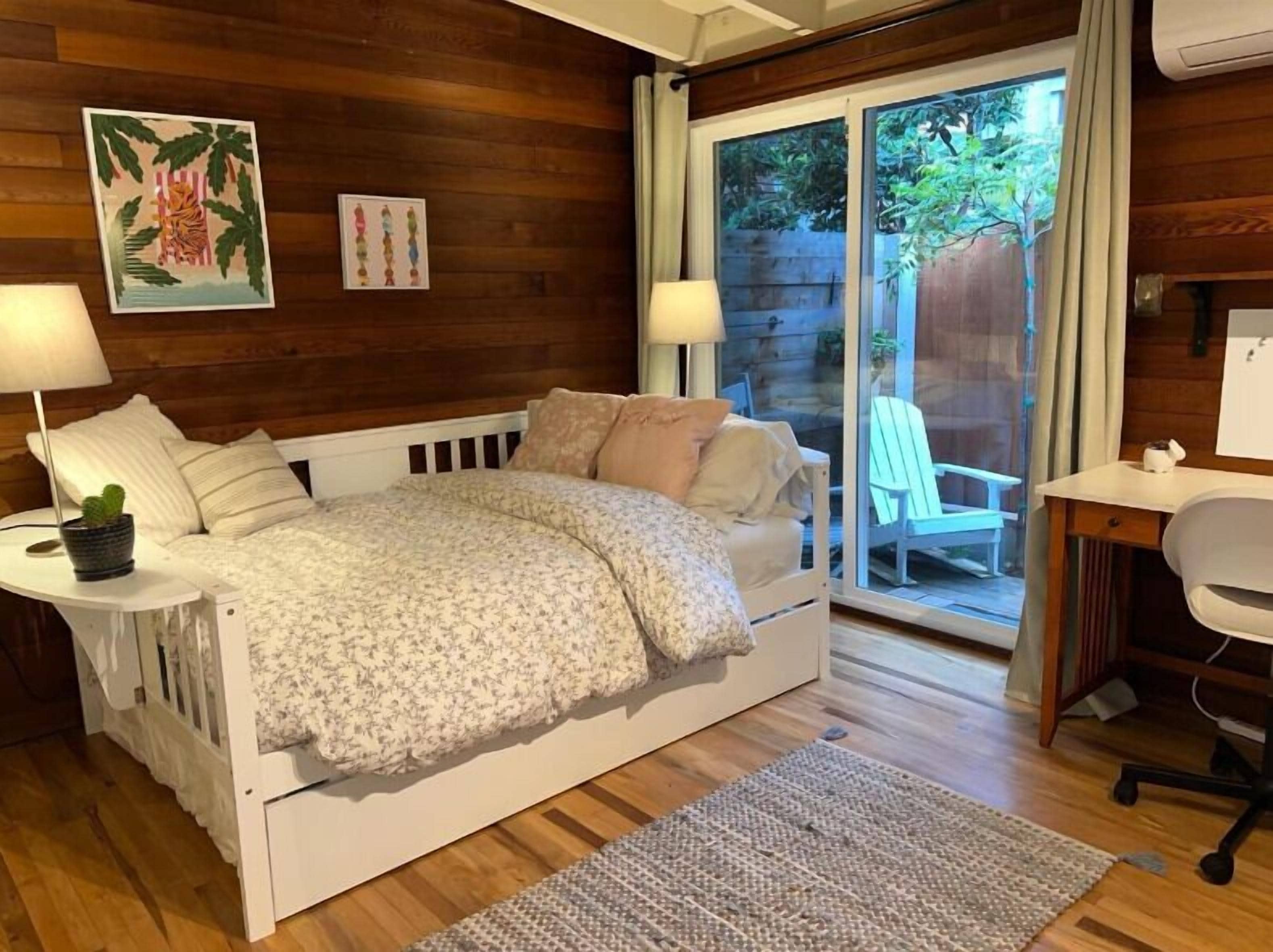 A bedroom with a bed, bedside tables, a desk, and a chair.