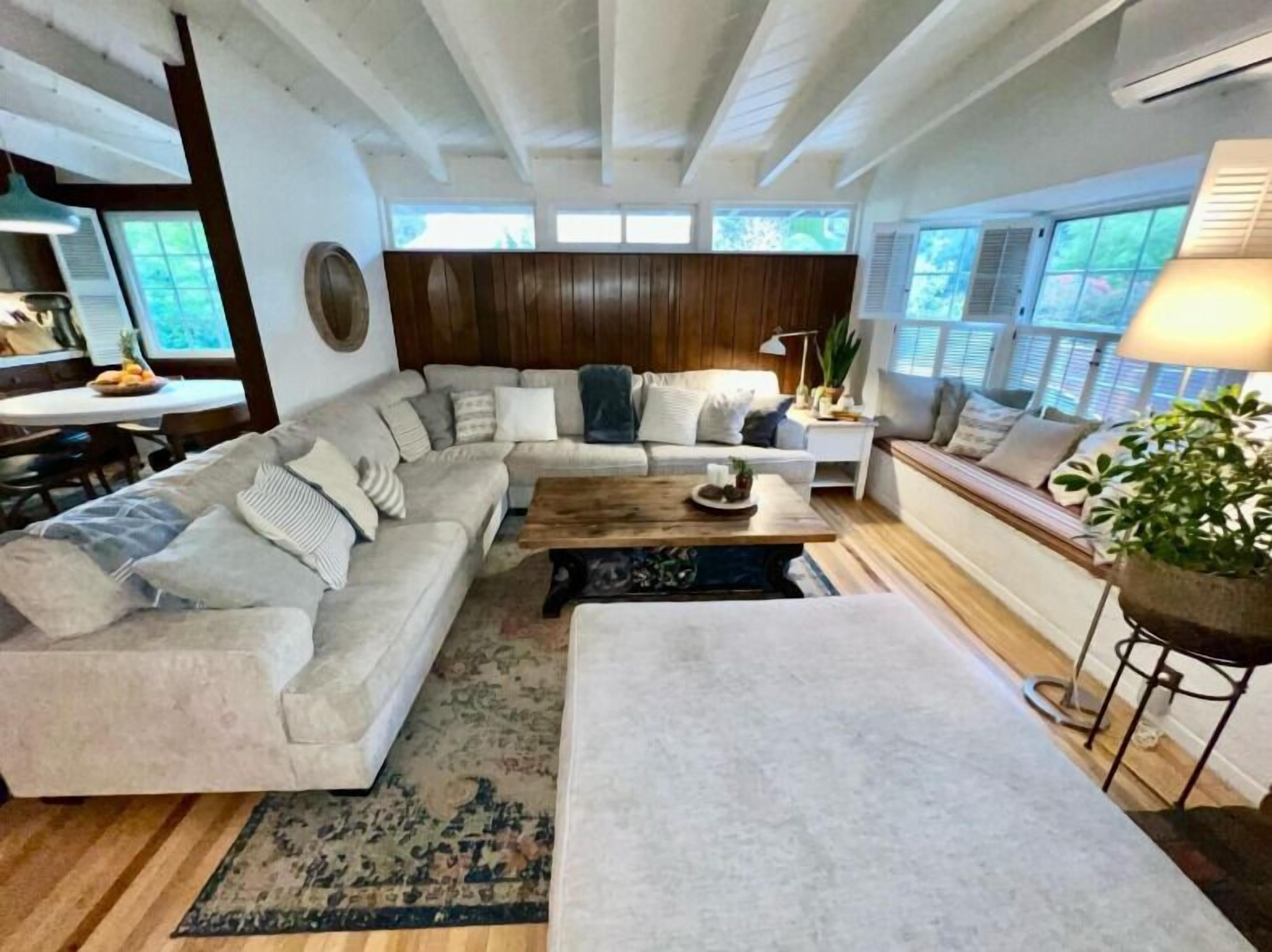 A spacious living room with a large sectional sofa, a coffee table, and a seating area with a bench.