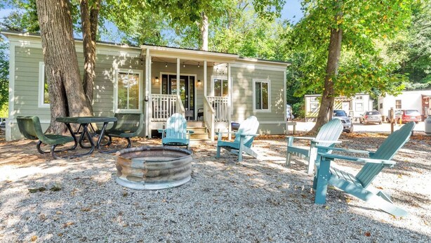 A cabin with a porch, outdoor seating, and a fire pit.